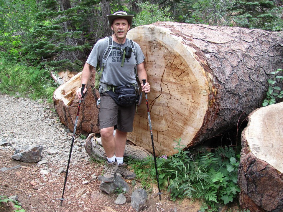 Greg by a cut tree on the trail